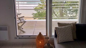 Une pièce dotée d’une grande porte-fenêtre coulissante donnant sur un balcon avec vue sur la plage et l’océan.