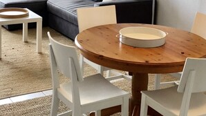 Un salon moderne avec un canapé d’angle, une table ronde en bois et une lampe blanche.
