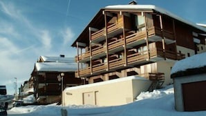 Un edificio de estilo chalet de madera con varios balcones, rodeado de nieve.