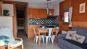 Una cocina acogedora con armarios de madera, una mesa de comedor con sillas y un sofá gris con cojines decorativos.