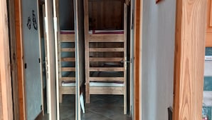 Un pasillo estrecho con paredes y suelos de madera, que conduce a una habitación con literas.