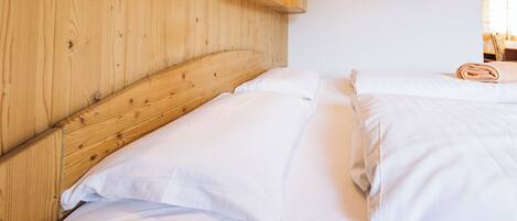 A wooden headboard with a shelf above a bed, a framed picture on the wall, and a neatly made bed with white linens.