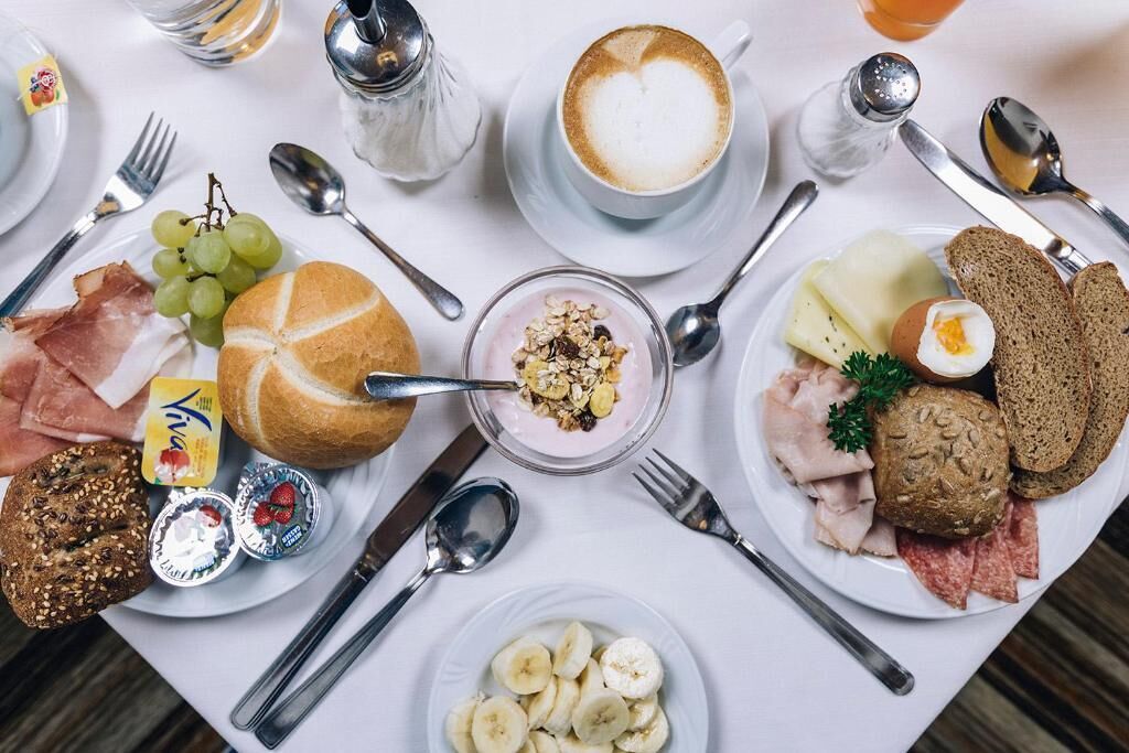 A breakfast setting with various food items and utensils on a table.