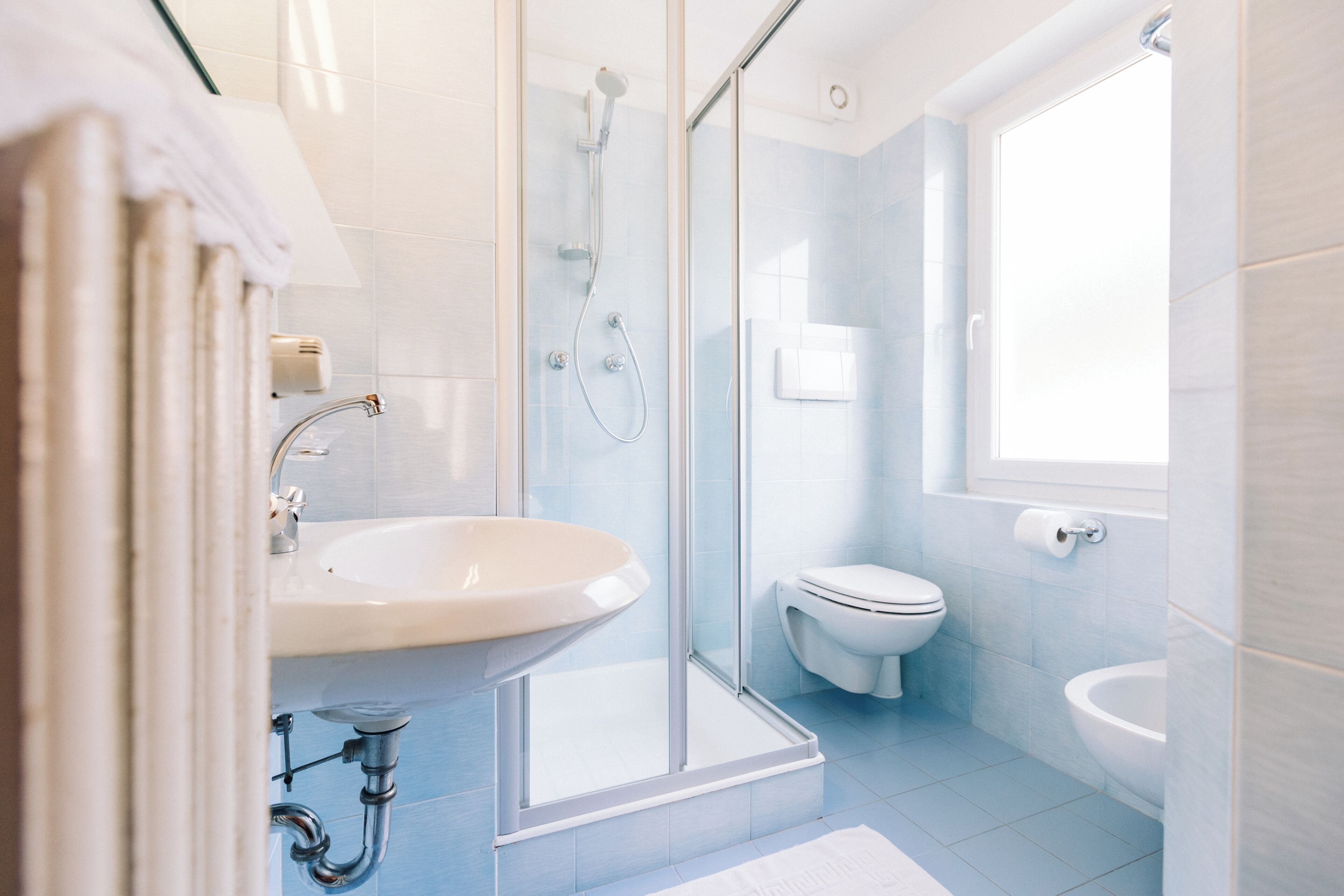A modern bathroom with a glass shower enclosure, a white sink, and a toilet.