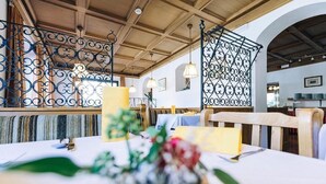 Ein Restaurantinneres mit Holzbalkendecken, Metallzierteilungen und einem Tisch, gedeckt mit einem Blumenstrauß.