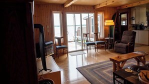 A wooden interior with a dining area, a sofa, and a kitchen area.