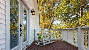 A wooden deck with a rocking chair and a white railing.
