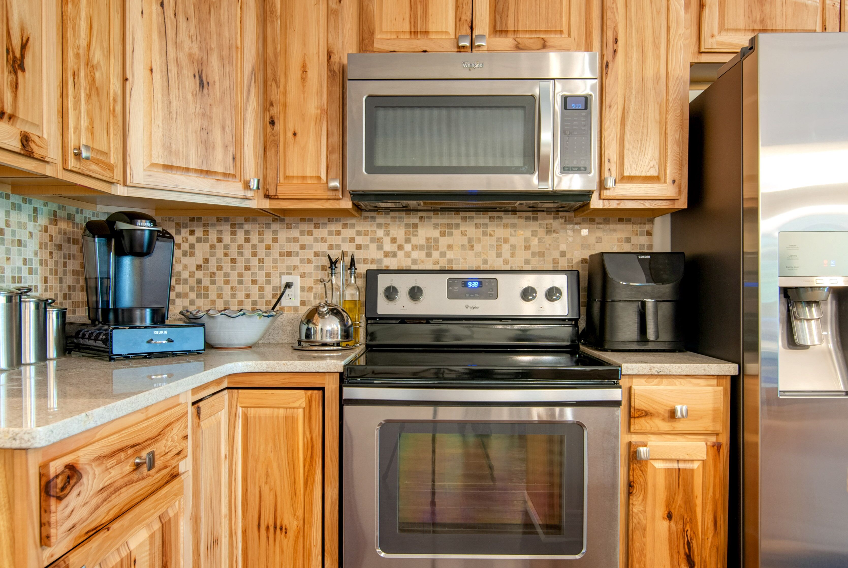 Une cuisine avec des meubles de rangement en bois, un four à micro-ondes, une cuisinière et une machine à café.
