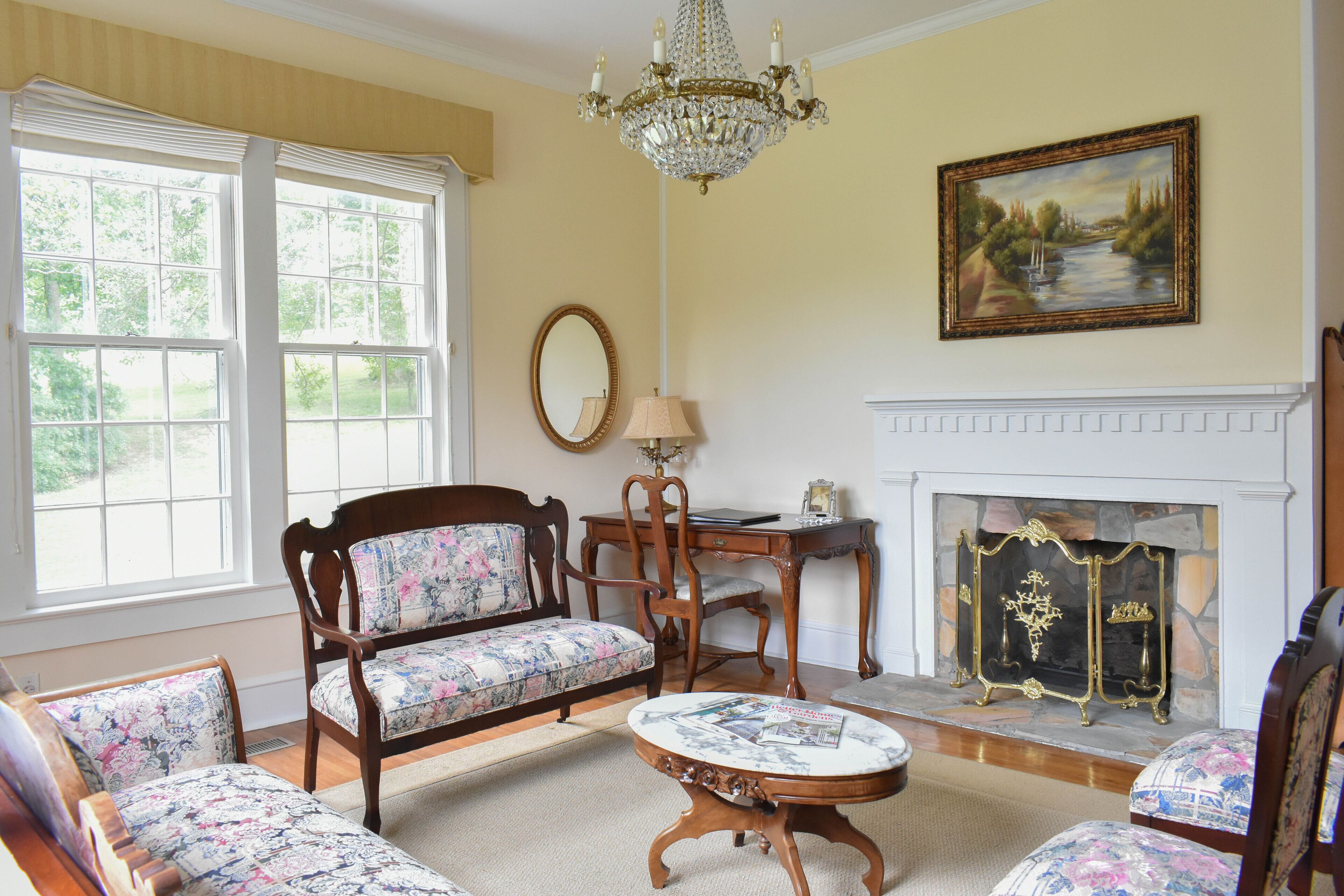 A traditional living room with a fireplace, floral upholstered furniture, and a chandelier.