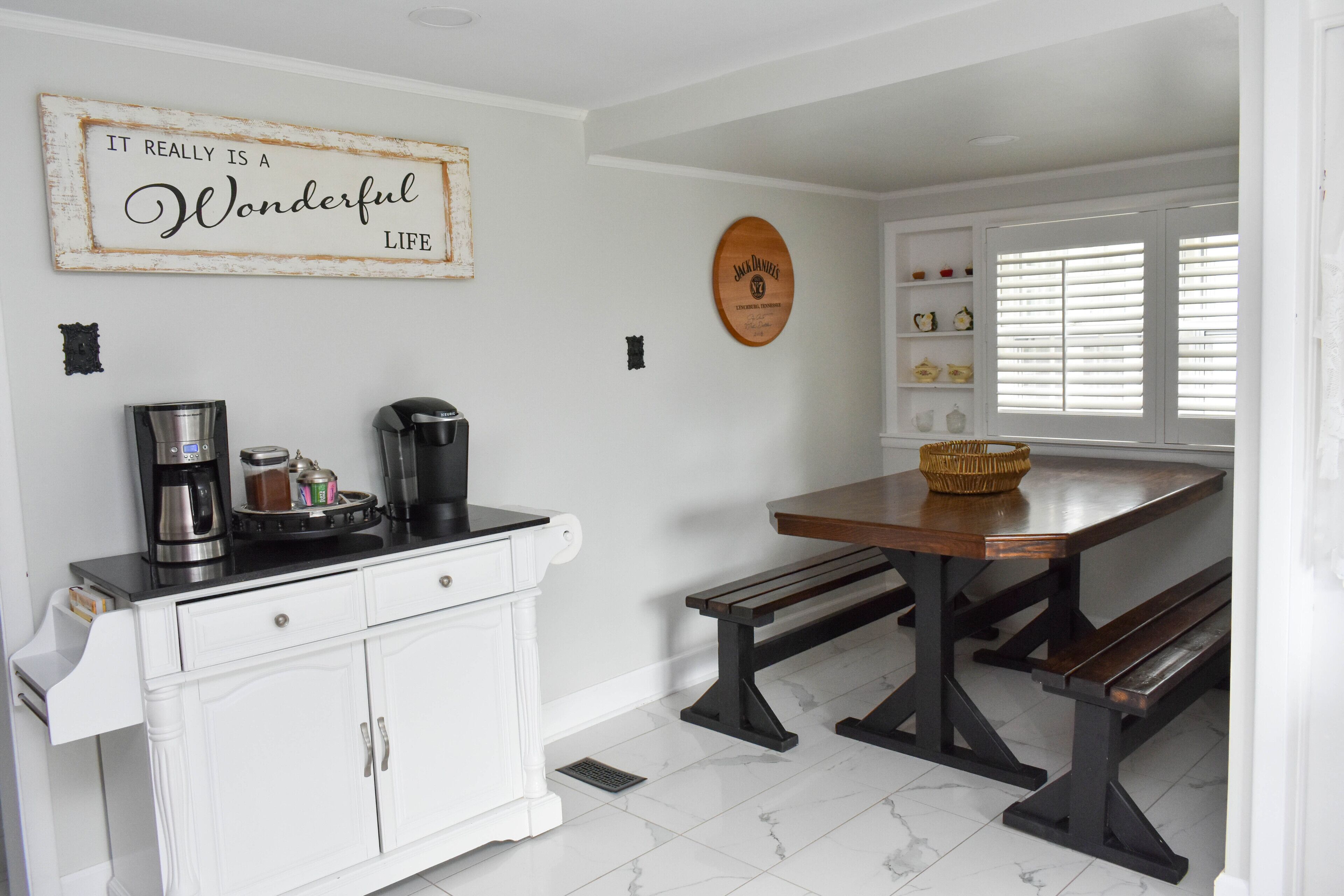 A kitchen with white cabinetry, a coffee maker, a toaster, and a wooden sign on the wall.