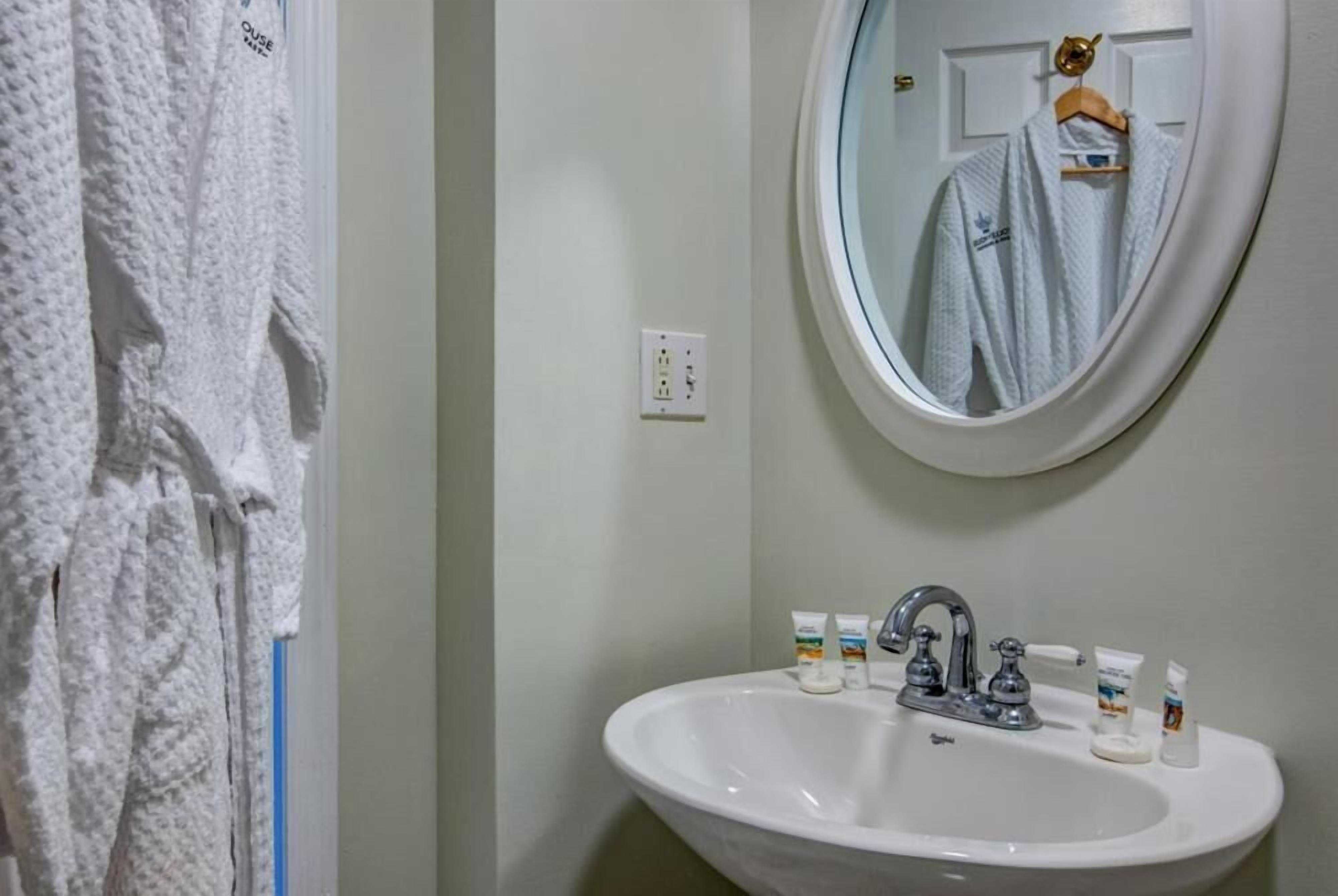 Un baño con un lavamanos blanco, un espejo y un perchero para toallas.