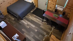 Une pièce dans un chalet en bois, comprenant un lit, un bureau, une chaise et une porte.