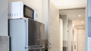 A modern kitchen with a stainless steel refrigerator, a microwave, and a wooden door. - La Montrucca camere (Caselle Torinese)