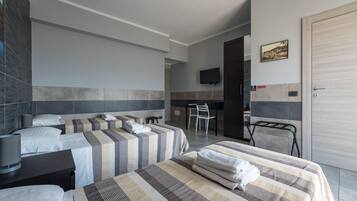 Ett hotellrum med två sängar, ett skrivbord, en stol och en tv på väggen.