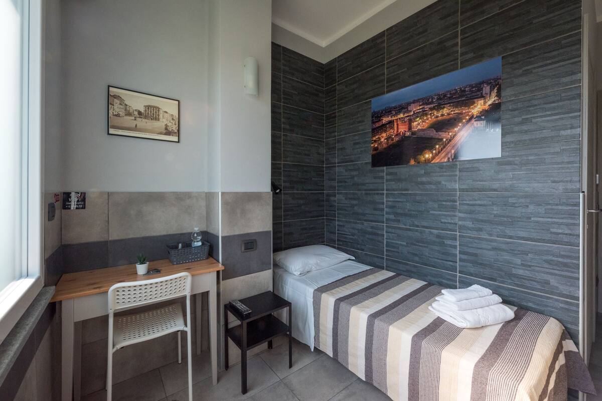 Una habitación de hotel moderna con una cama, un escritorio, una silla y una mesita.