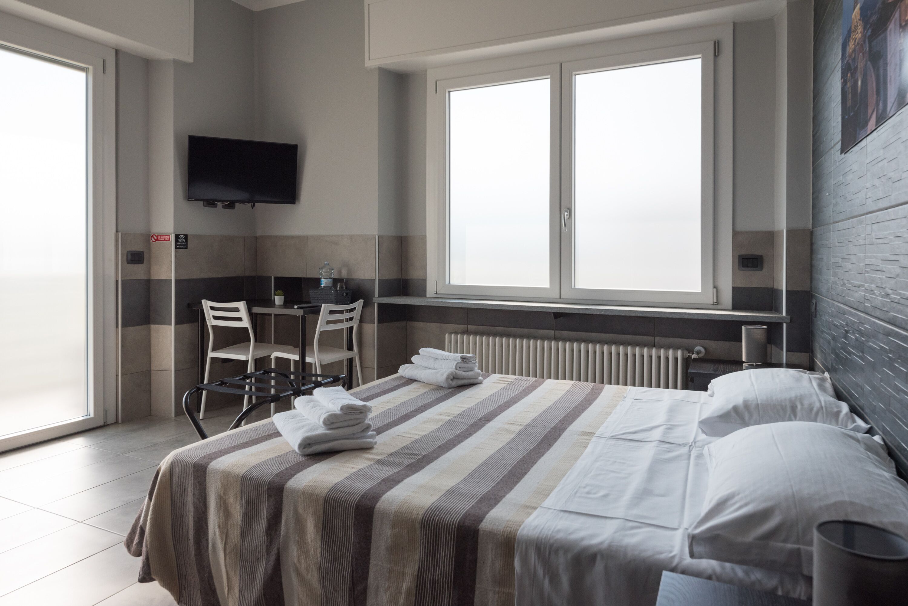 A hotel room with a bed, a desk, a chair, a TV, and a window.