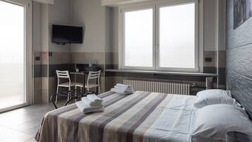 Une chambre d’hôtel avec un lit, un bureau, une chaise, une télévision et une fenêtre.