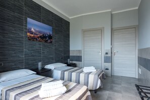 A hotel room with two beds, a large cityscape picture on the wall, and a closed door. - La Montrucca camere (Caselle Torinese)
