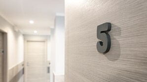 A hallway with a wooden wall and a number '5' sign. - La Montrucca camere (Caselle Torinese)