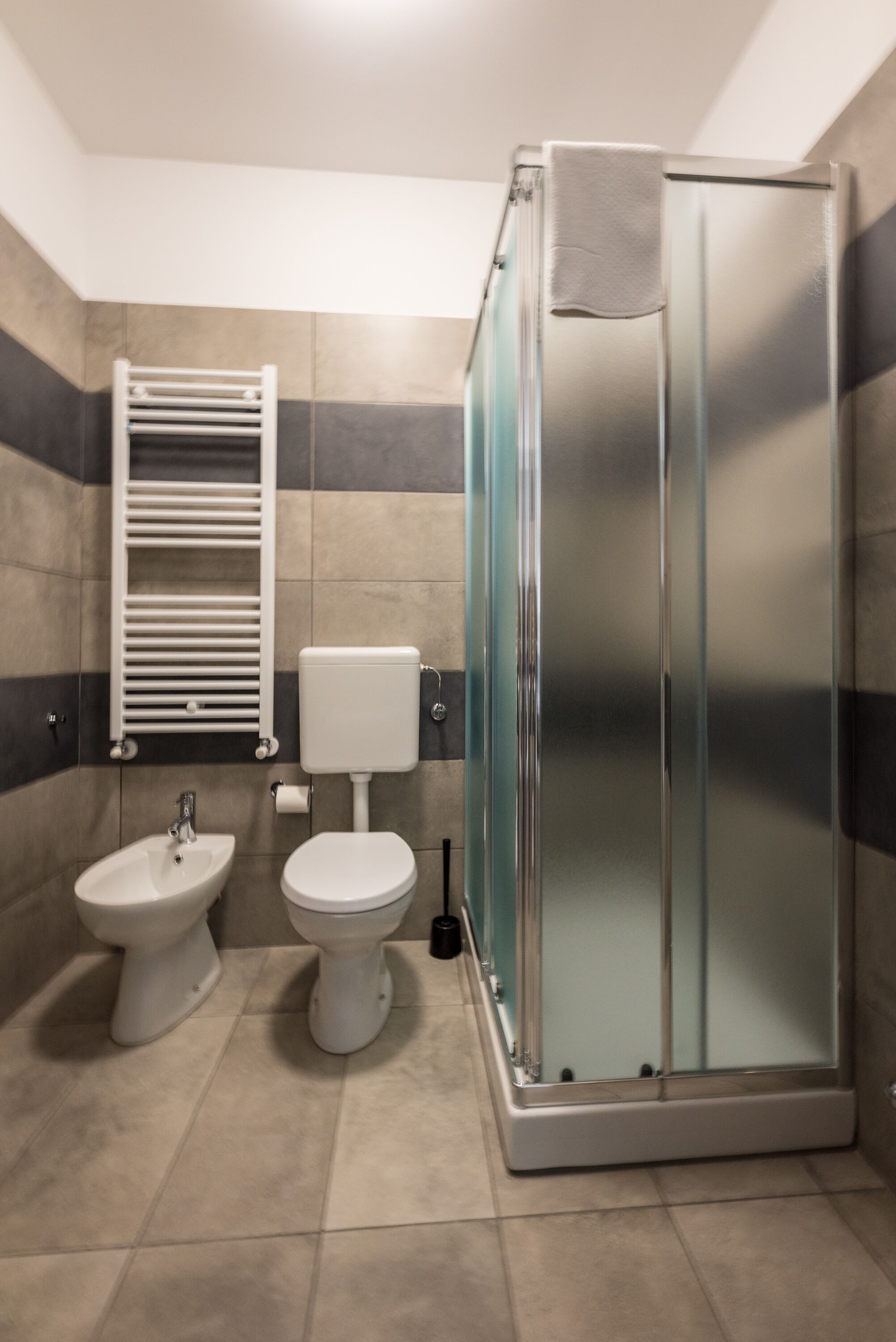 A bathroom with a glass-enclosed shower, a bidet, and a toilet.