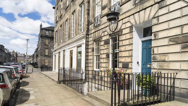A street with parked cars, a building with a blue door, and a black metal fence. - Stylish City Centre Apartment (Edinburgh)