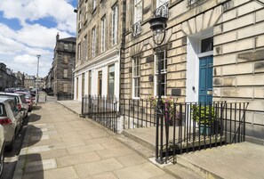A street with parked cars, a building with a blue door, and a black metal fence. - Stylish City Centre Apartment (Edinburgh)
