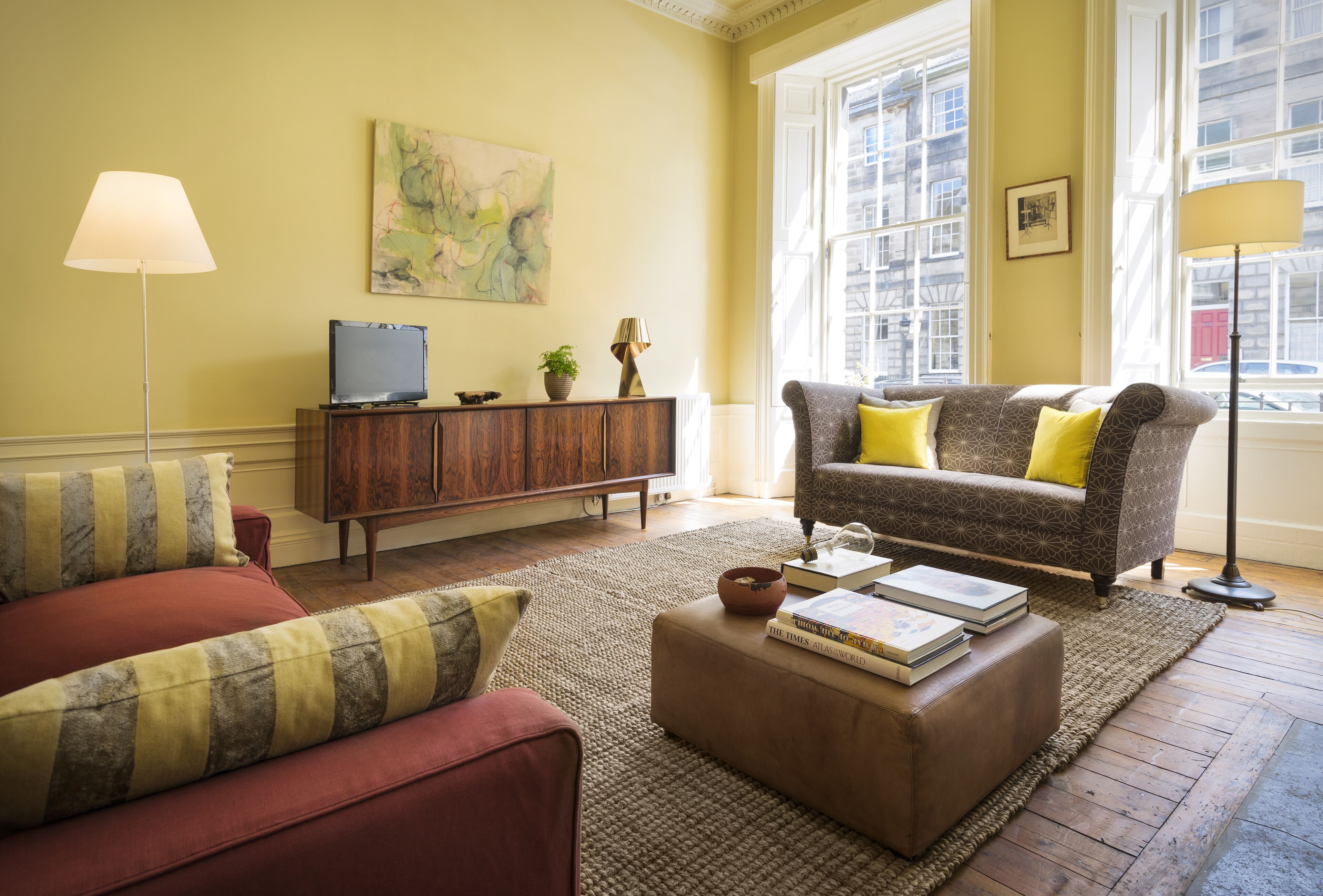 A living room with a sofa, ottoman, and a television on a wooden cabinet.