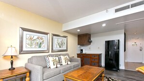 A living room with a sofa, coffee table, and framed botanical prints on the wall. - Pool & close to Beaches, Elegant King Bed Studio (Sleeps 4) FREE Parking! (Honolulu)