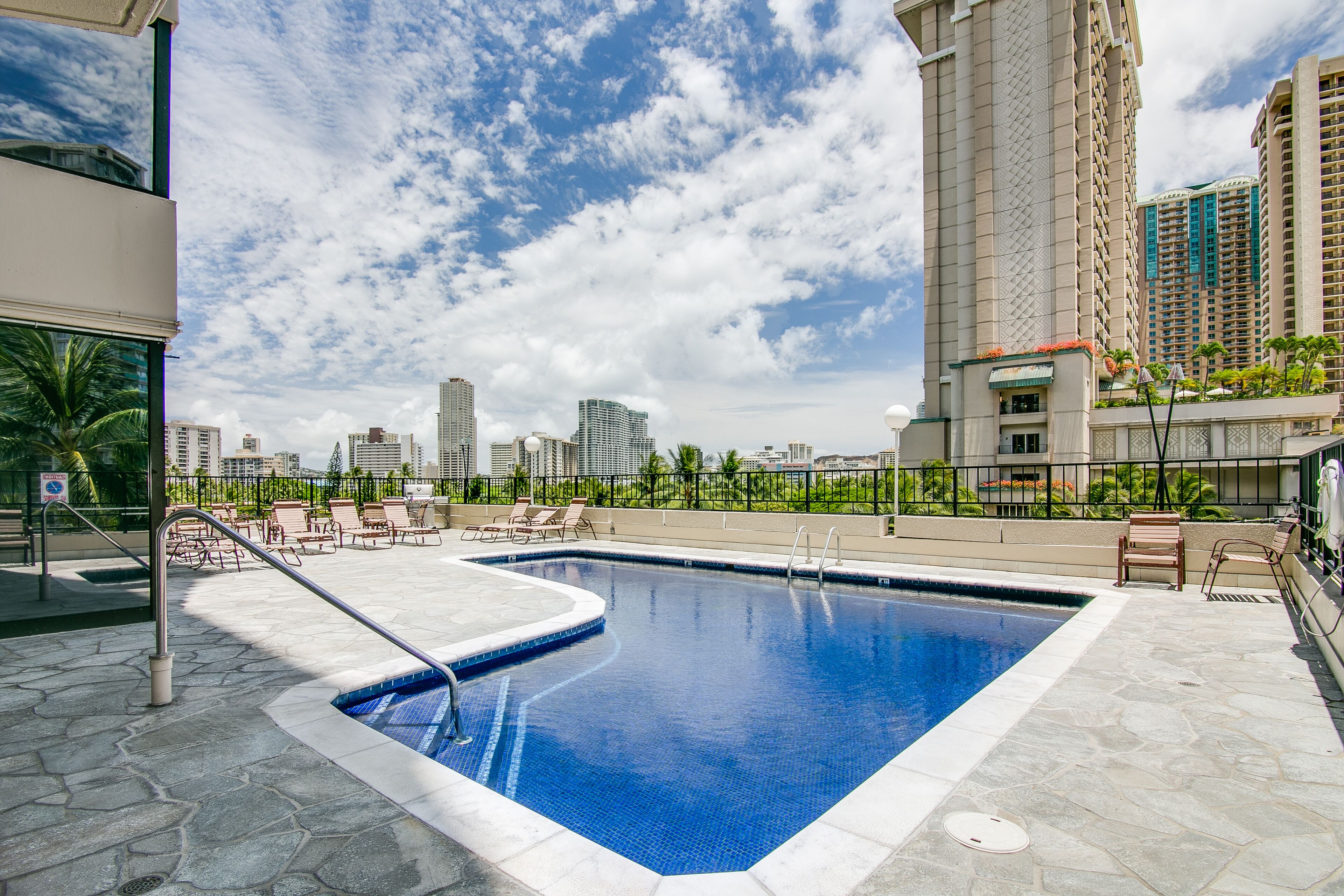 A swimming pool with lounge chairs and a view of tall buildings in the background.