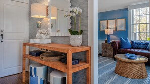 A room with a wooden console table, a large mirror, and a potted orchid. - Anchor Inn (Nantucket)
