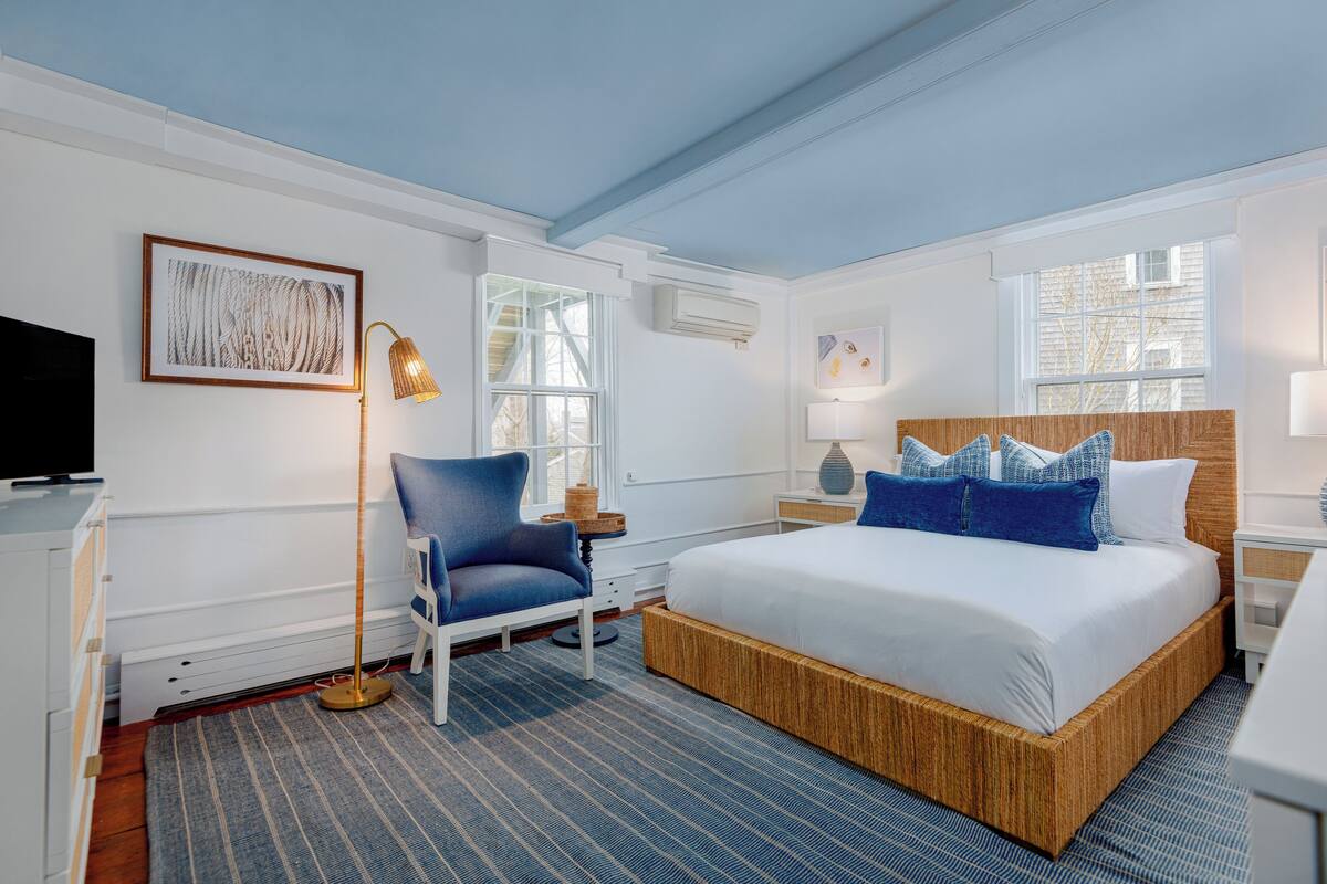 Quarto de hotel com uma cama grande, uma cadeira, uma televisão e uma janela.