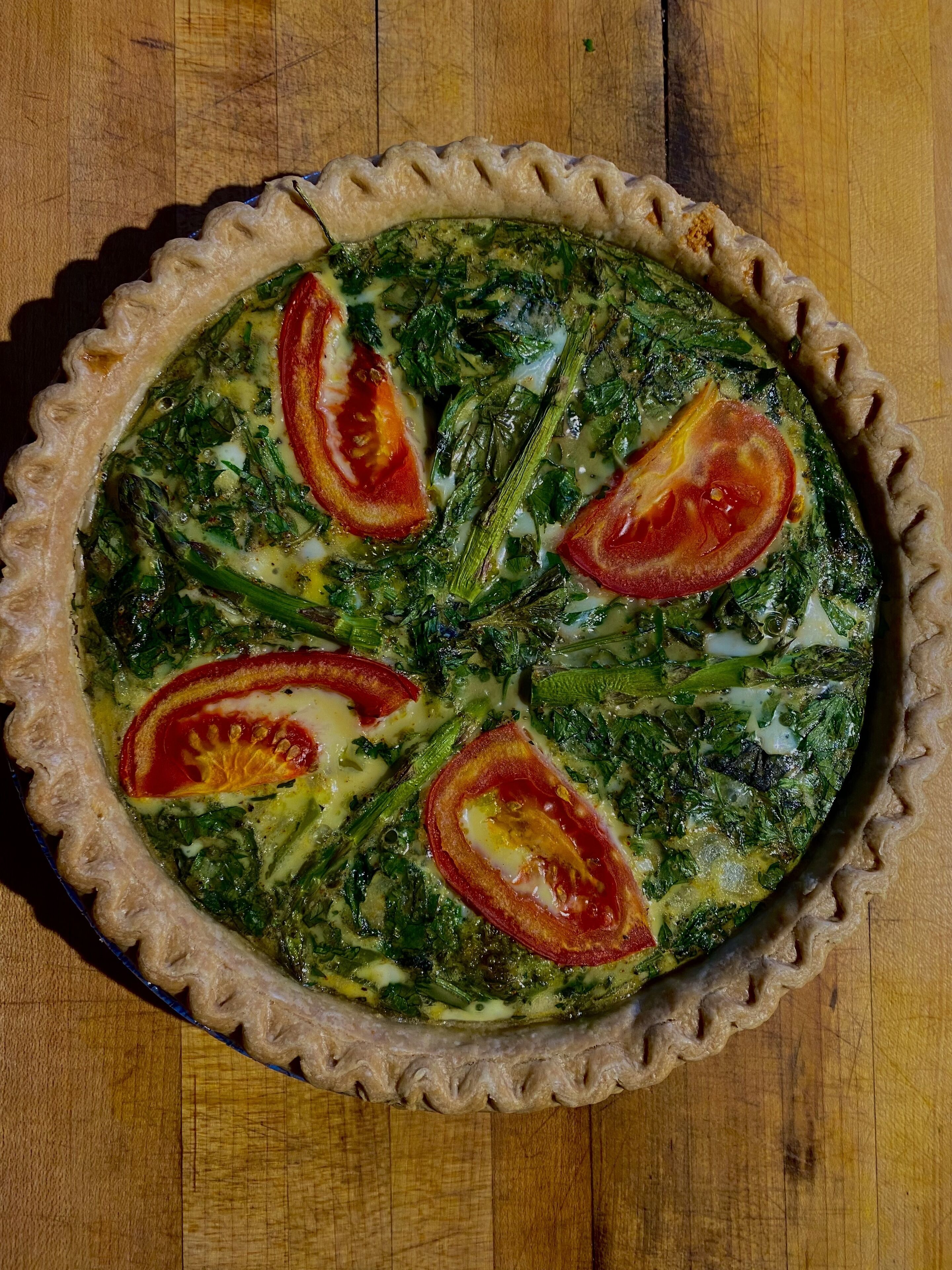 Une quiche aux épinards et aux tomates, servie dans un plat à tarte.