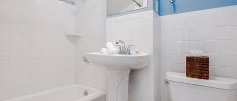 Un baño con una bañera blanca, un lavamanos blanco y un inodoro.
