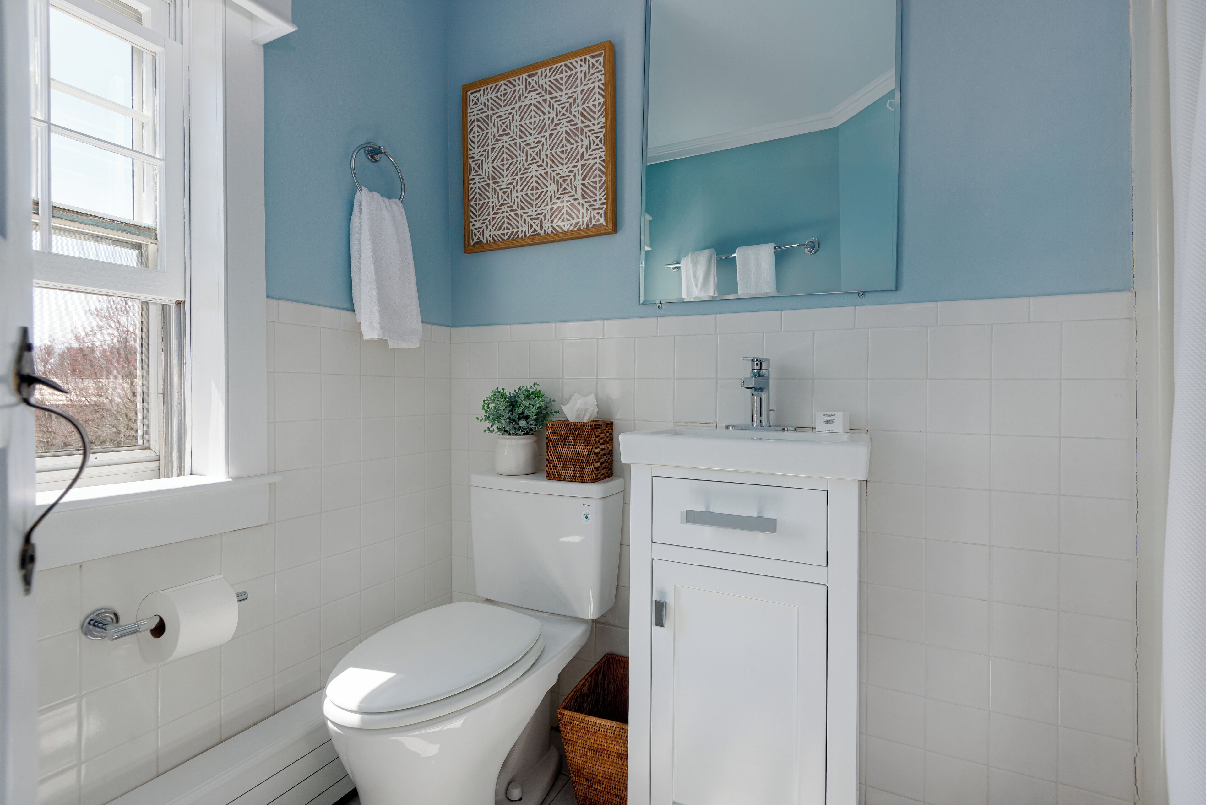 Une salle de bain avec des toilettes, un lavabo, un miroir et une fenêtre.