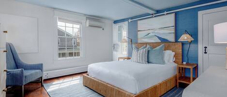 A bedroom with a large bed, a chair, a bedside table, and a painting on the wall.