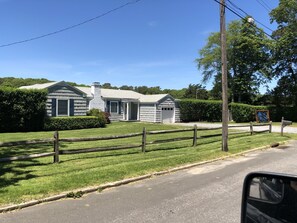 Ein eingeschossiges Haus mit Garage, umzäunter Garten und blauem Himmel.