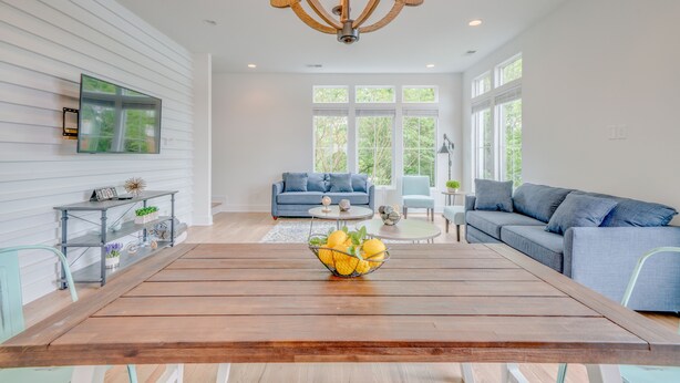 A modern living room with a wooden dining table, a blue sofa, and a chandelier.