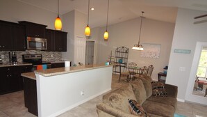 A modern kitchen with dark cabinets, a central island, and pendant lighting. - Casa del Mar (Port Charlotte)