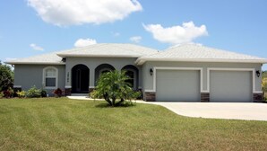 A single-story house with a grey roof, a front entrance, and two garage doors. - Casa del Mar (Port Charlotte)