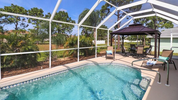 Un espace piscine doté d’un patio couvert et de mobilier d’extérieur.