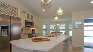 A modern kitchen with a large island, stainless steel appliances, and pendant lighting. - Blue Marlin (Port Charlotte)