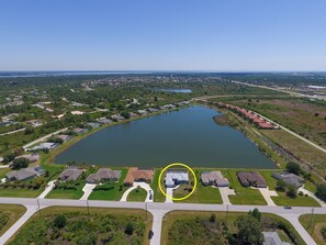 An aerial view of a residential area with a large lake, houses, and a highlighted building circled in yellow. - Blue Marlin (Port Charlotte)