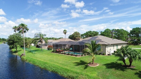 Una casa con piscina, terraza cubierta y un río.