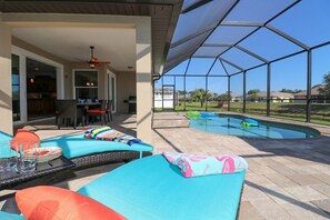 Un espacio al aire libre techado con piscina, sillas de descanso y un patio con mesa y sillas.