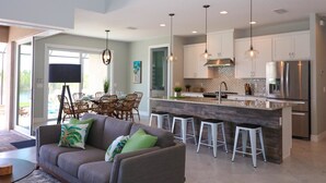 Una cocina moderna con una isla central, taburetes de bar y electrodomésticos de acero inoxidable.