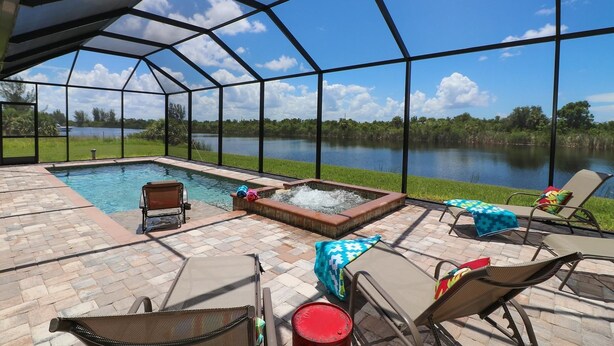 Un espacio al aire libre techado con piscina, sillas de descanso y bañera de hidromasaje.