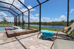 Ein mit Gittern versehener Patio mit Whirlpool, Liegestühlen und Seeblick.