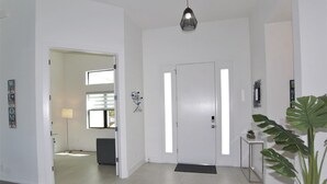 Ein modernes Interieur mit einer weißen Tür, einer schwarzen Pendelleuchte und einem Blumentopf.