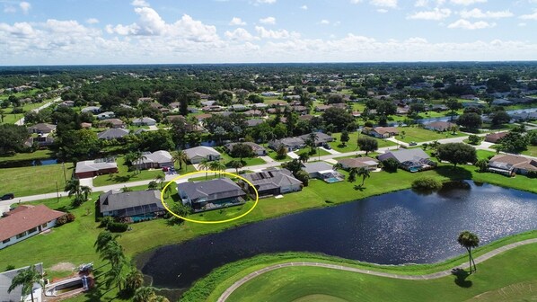 Vista aérea de una zona residencial con casas, una gran masa de agua y una casa destacada con piscina.