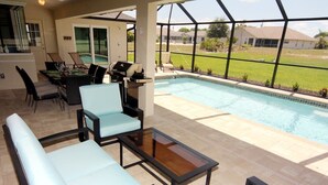 An outdoor patio area with a pool, seating, and a grill. - Lazy Gator (Rotonda West)